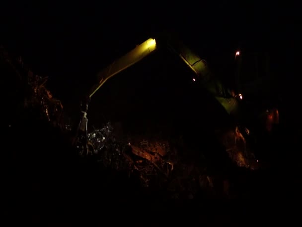 Chargement de ferraille par un grand manipulateur la nuit .