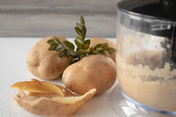 Beyaz zemin üzerinde bir karıştırıcıda soyulmuş patates karışık.