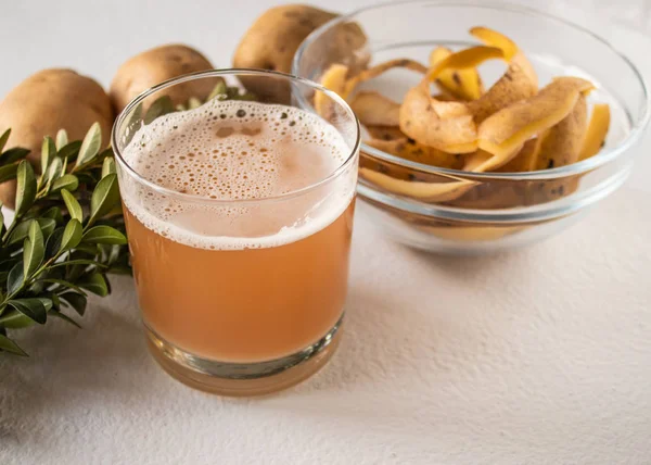 Patates suyu bir bardak bütün patates ve skarlupa yakın.