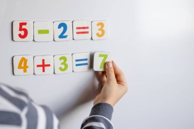 Çocuk matematiksel örnekler çözdü. Bir çocuk bir tahta üzerine örnekler çözer.