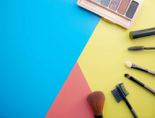 Makeup and makeup brushes, eye shadows on a colored background. Cosmetics for the face. With empty space on the left.
