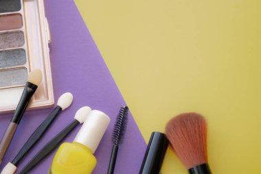 Kozmetik aksesuarları. Sarı, mor arka planda allık, fırça, vernik için fırça.