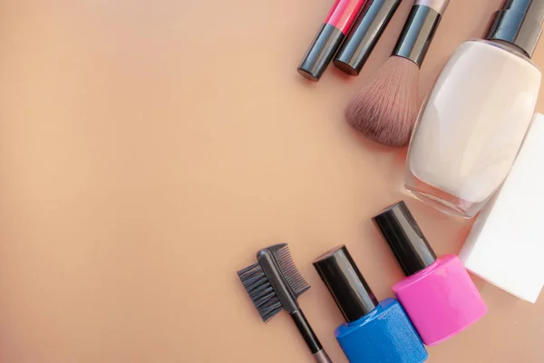 Cosmetic accessories. Brush, blush, lipstick, cream, nail polish on a yellow, cream background.