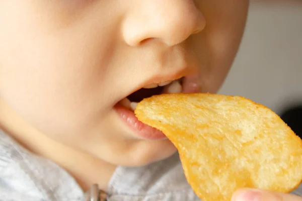 Baby eating chips. Close-up. The child holds the chips.