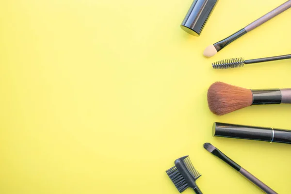 Makeup brushes, brushes for everyday makeup. Cosmetic items on yellow background, closeup.