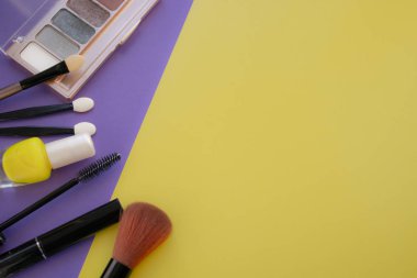 Kozmetik aksesuarları. Sarı, mor arka planda allık, fırça, vernik için fırça.