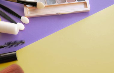 Kozmetik aksesuarları. Sarı, mor arka planda allık, fırça, vernik için fırça.