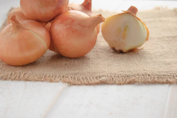 Fresh onion on wooden background and on burlap. Ripe onions Allium cepa or onions or vegetarian and vegan food.