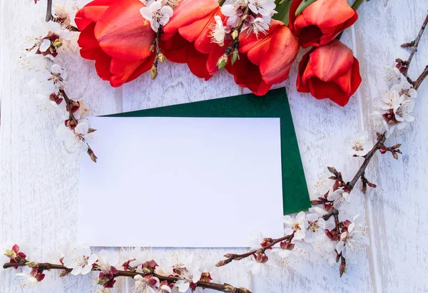 En bukett Röda tulpaner och grenar av vita blommor mot vita tavlor. Plats för text. Konceptet våren har kommit. — Stockfoto