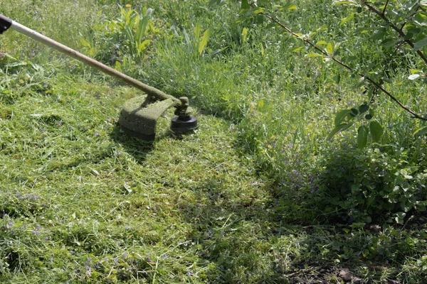 一个用手动割草机的人割草 — 图库照片
