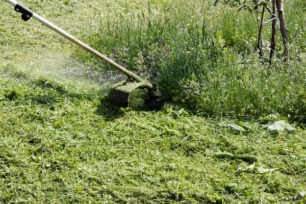 Ein Mann mit einem manuellen Rasenmäher mäht das Gras — Stockfoto
