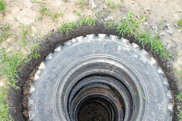 Poço de esgoto com pneus de carro . — Fotografia de Stock