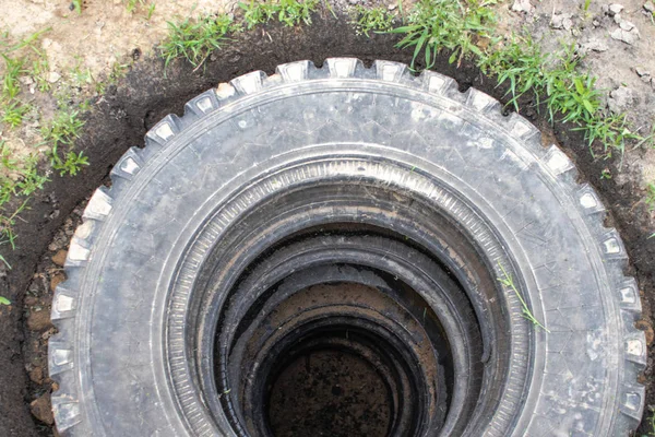 Poço de esgoto com pneus de carro . — Fotografia de Stock