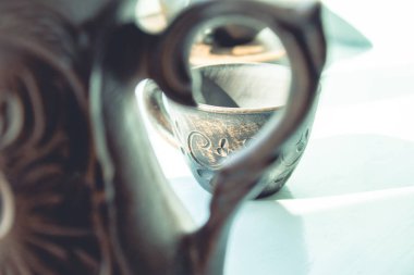 Ön planda bir çaydanlık ve pencerenin yanında bir fincan kil duruyor..