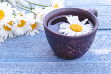 Ahşap mavi arka plan üzerinde papatya bir buket ile papatya çay Fincan.