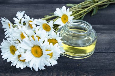 Papatya çiçekleri yakınındaki tahtalarda hafif papatya esansiyel yağ bir banka var.