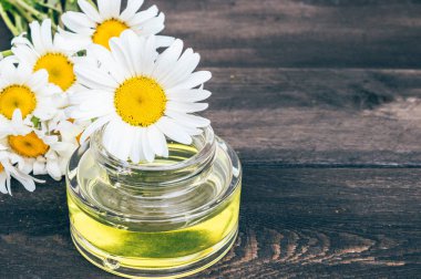 Papatya çiçekleri yakınındaki tahtalarda hafif papatya esansiyel yağ bir banka var.