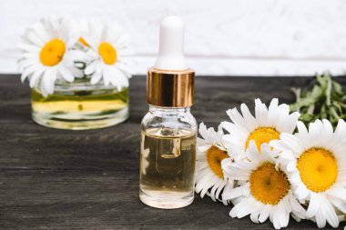 Bir pipet ile cam şişede Papatya uçucu yağ papatya çiçekleri yakınında masada.