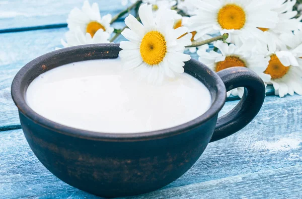 Beyaz küçük çiçekleryanında süt lü bir fincan. — Stok fotoğraf