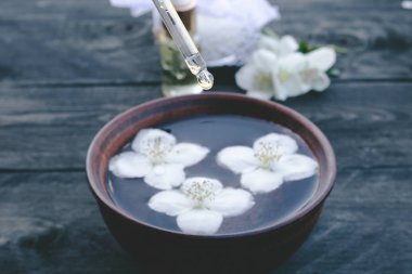 Ahşap masa arka planda Jasmine esansiyel yağı ve çiçekler.