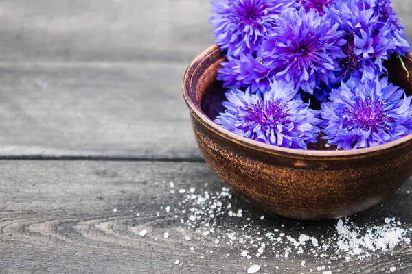 Kék cornflowers hazugság a vízben egy tálban a háttérben a régi táblák. — Stock Fotó