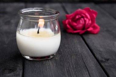 Eski bir tahtada gül ve yanan mum. Çiçek çerçevesi.
