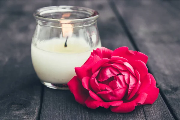 Rosa y vela encendida en una vieja tabla de madera. Marco de flores . —  Fotos de Stock