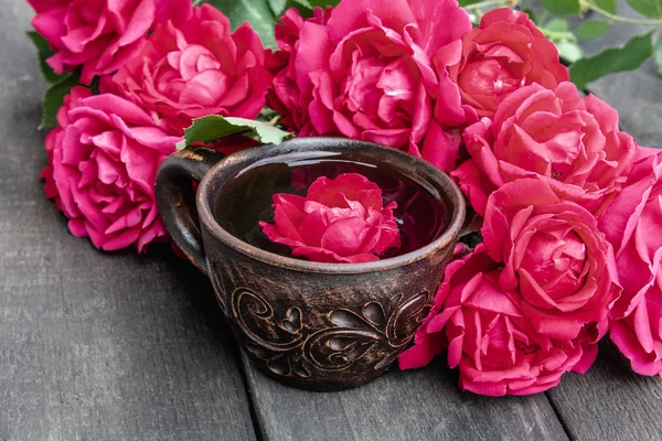 Чай из лепестков чайной розы в чашке на деревянном деревенском фоне . — стоковое фото