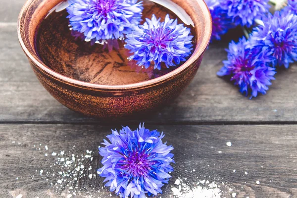 Fiori di mais blu si trovano in acqua in una ciotola sullo sfondo di vecchie tavole . — Foto Stock