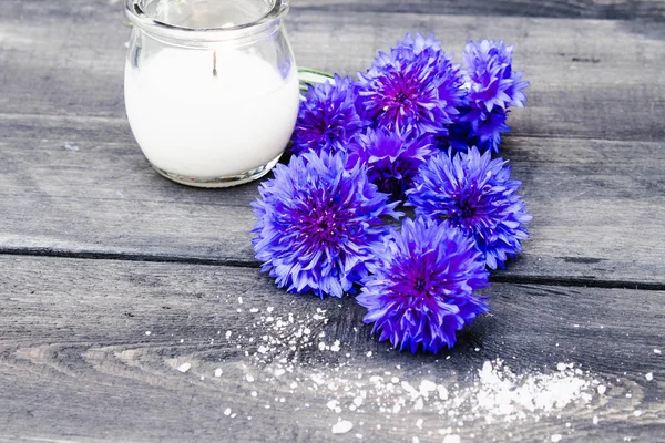 Kék cornflowers és egy égő gyertyát a háttérben a régi táblák. — Stock Fotó