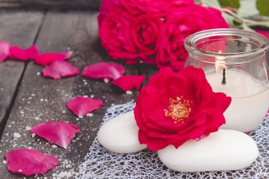 Kırmızı güller ve koyu ahşap arka plan üzerinde sıcak bir mum ile doğal kozmetik sabun.