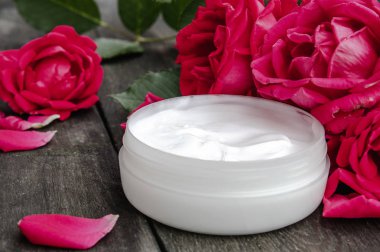 Ahşap rustik arka plan üzerinde bir cam kavanozda yüz ve vücut bakımı için kırmızı pembe çiçekler ile Doğal çiçek kozmetik