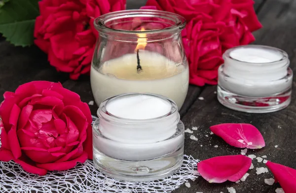 kozmetik krem ve yaprakları ve eski ahşap arka plan üzerinde yanan bir mum ile gül.