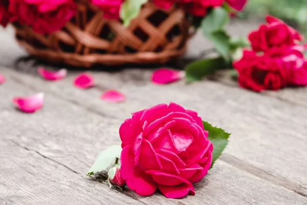Букет красных роз в корзине на деревянном фоне . — стоковое фото