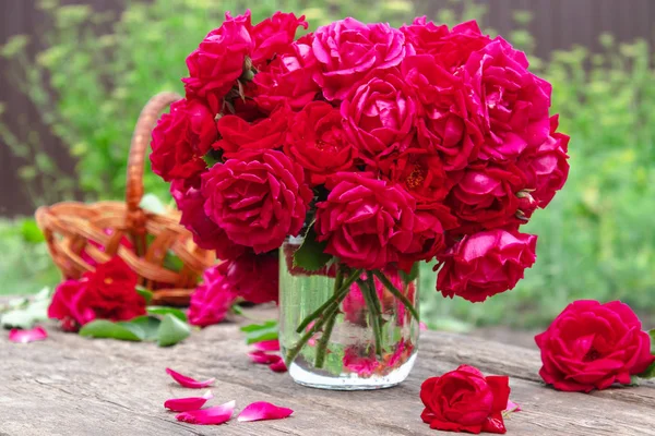 Букет красных роз в вазе на фоне зеленой травы . — стоковое фото