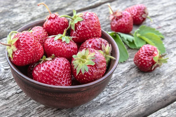 Fresh strawberries in a bowl on a wooden table. — Stock Photo, Image