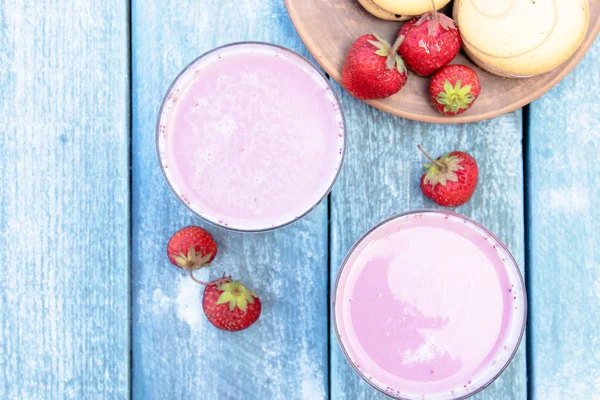 Cóctel con club de leche y bayas en un vaso sobre el fondo de las tablas azules . — Foto de Stock