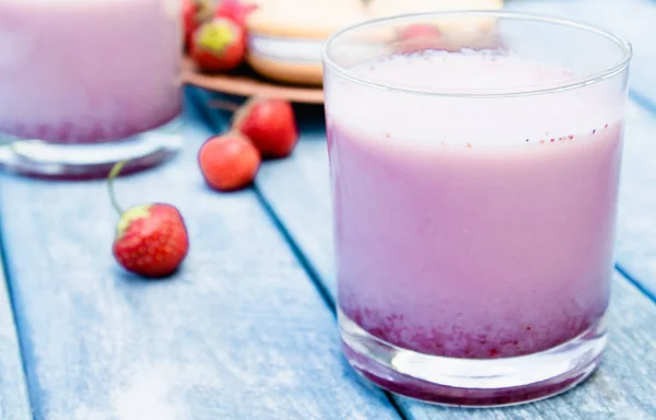 Cóctel con club de leche y bayas en un vaso sobre el fondo de las tablas azules . — Foto de Stock