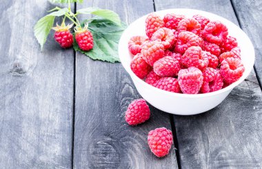 Eski koyu kurulların arka planda bir kase üzerinde olgun kırmızı ahududu. Seçici odaklama.