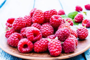 Mavi panoları arka plan karşı bir kase üzerinde olgun kırmızı ahududu. Seçici odaklama.