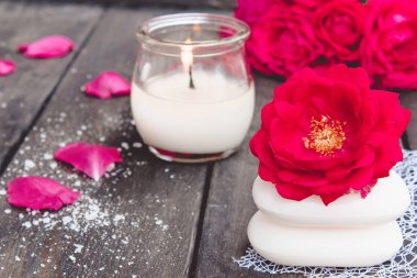 Kırmızı güller ve koyu ahşap arka plan üzerinde sıcak bir mum ile doğal kozmetik sabun.