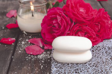 Kırmızı güller ve koyu ahşap arka plan üzerinde sıcak bir mum ile doğal kozmetik sabun.