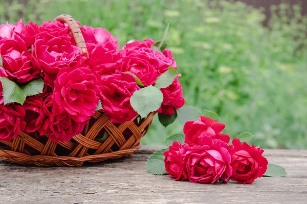 Ahşap bir arka plan üzerinde bir sepet içinde kırmızı gül bir buket.