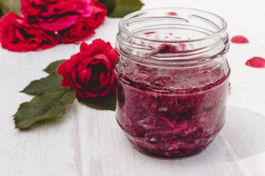Hafif bir arka plan üzerinde cam bir kavanozda gül yaprakları Reçel. Çiçek sırı. Sağlıklı gıda.