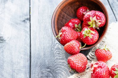 olgun kırmızı çilek çuval bir masaya dağınık.