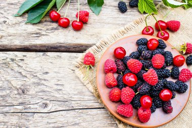 sulu taze lezzetli çilek ahududu, kiraz, ahşap arka plan üzerinde bir kase dut.