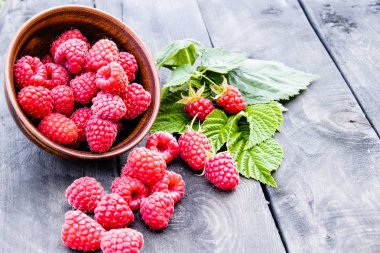 Eski koyu tahtaların arka planında yaprakları ile Taze ahududu. Seçici odaklama.