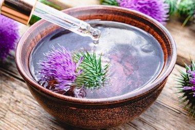 Ahşap arka planda thistle yağı ve devedikeni çiçekleri.