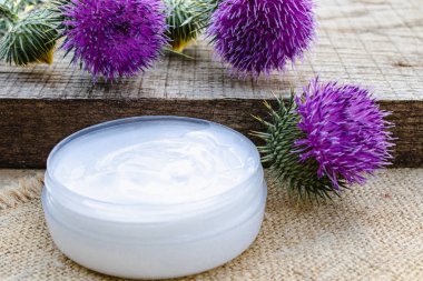 Ahşap arka plan üzerinde çiçek devedikeni ile Krem. Tıbbi bitki.