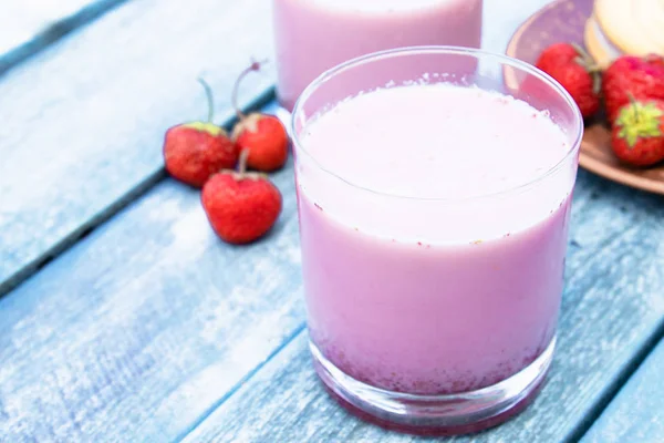 Cóctel con club de leche y bayas en un vaso sobre el fondo de las tablas azules . — Foto de Stock